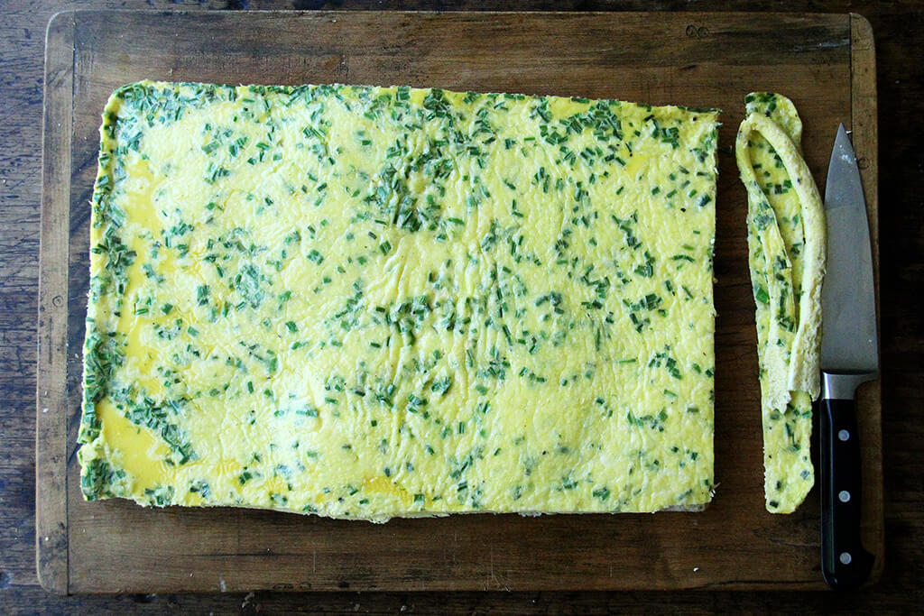 A cutting board with sheet pan eggs.