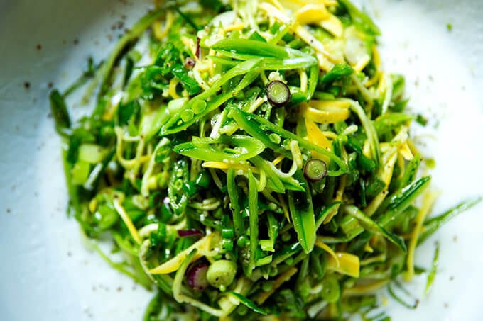 A bowl with buttermilk dressing and snap pea salad heaped on top. 