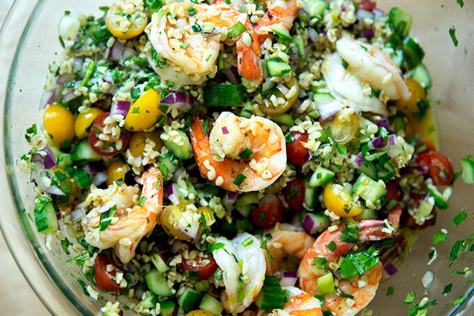 A bowl of tabbouleh with cilantro, lime, and grilled shrimp.