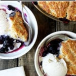 Two bowls of blueberry cobbler with buttermilk biscuits.