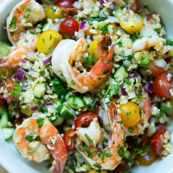 A bowl of tabbouleh with cilantro, lime, and grilled shrimp.