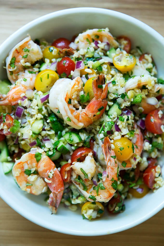 A bowl of tabbouleh with cilantro, lime, and grilled shrimp.