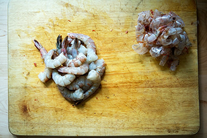 A board with peeled shrimp and shrimp shells. 