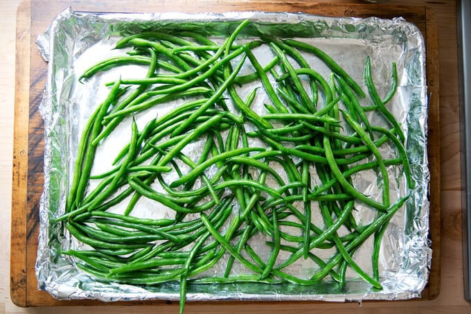 A foil-lined sheet pan covered with green beans.