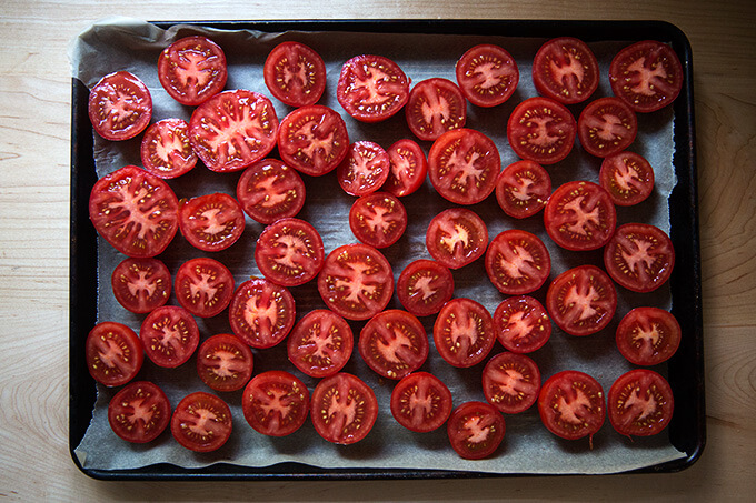 Halved tomatoes on a parchment-lined sheet pan.