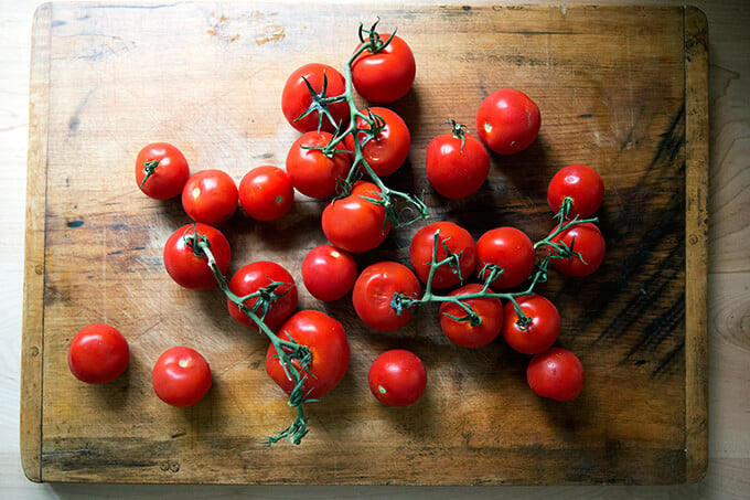 Tomatoes on the vine on a cutting board.