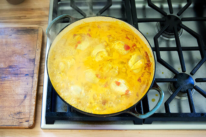 A sauté pan with curry sauce and chicken.