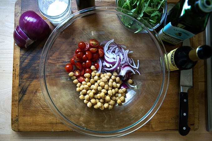 A large bowl of tomatoes, red onion, and cucumbers.