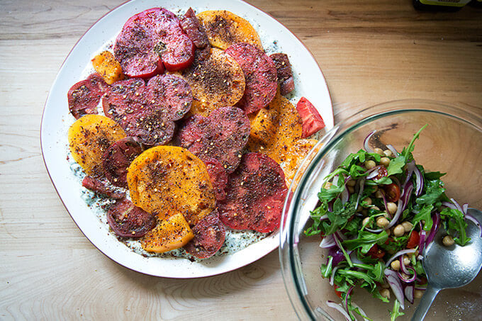 A platter of Israeli-spiced tomatoes aside a salad of greens.