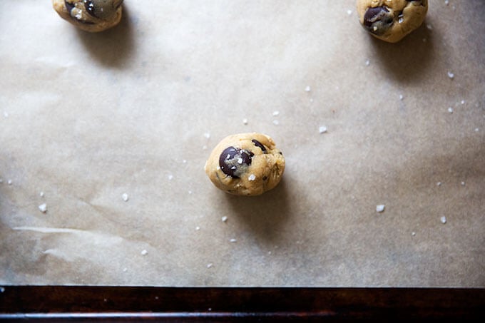 A gluten-free cookie dough ball on a sheet pan sprinkled with sea salt.