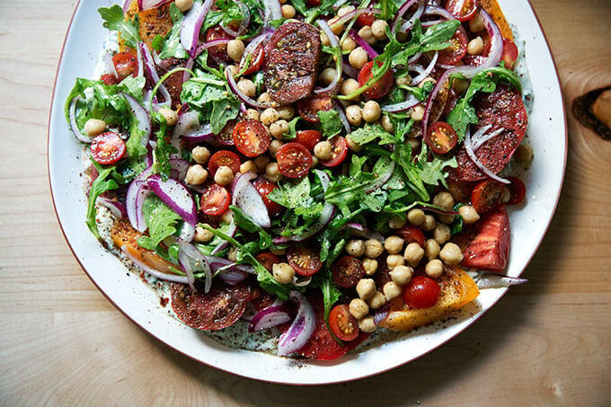 A platter of Israeli spiced tomato salad with cucumber yogurt sauce and chickpeas.