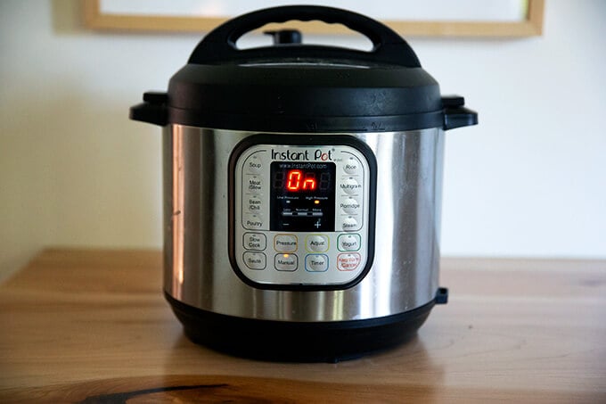 An Instant Pot on a counter turned on.