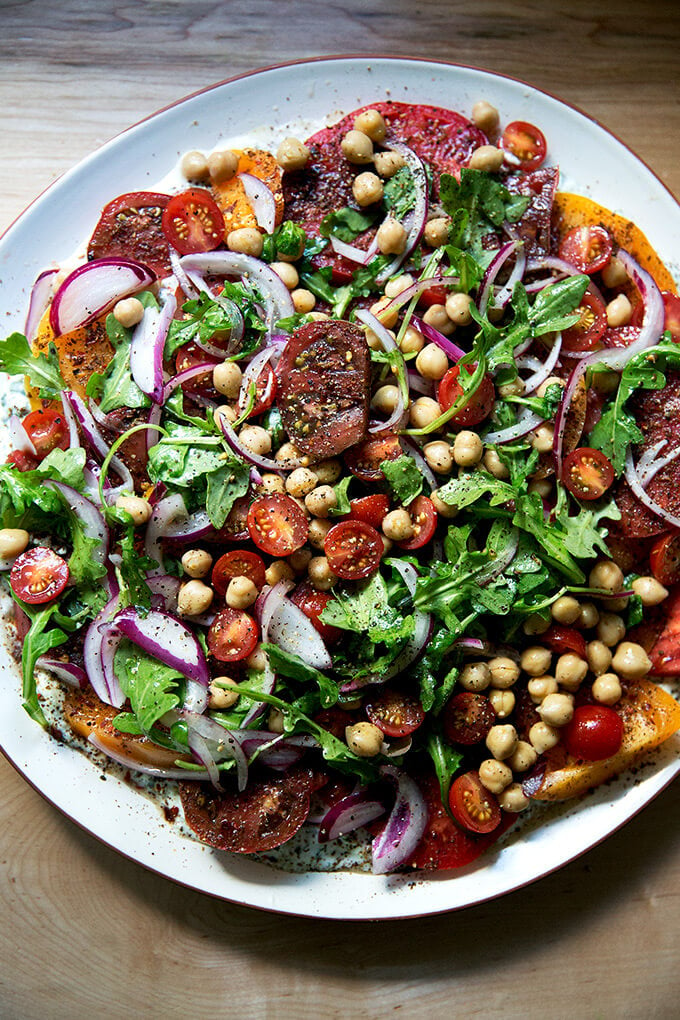 A platter of Israeli spiced tomato salad with cucumber yogurt sauce and chickpeas.