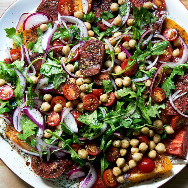 A platter of Israeli spiced tomato salad with cucumber yogurt sauce and chickpeas.