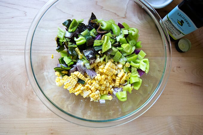 A bowl of raw corn, poblanos, red onion, olive oil, and salt.