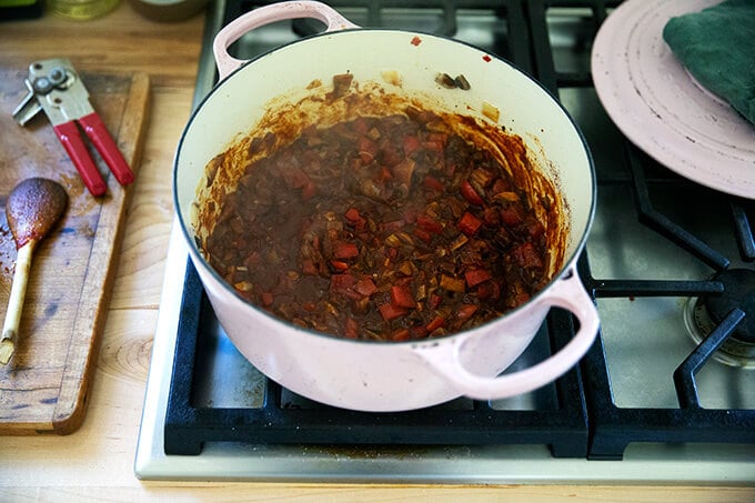 A large pot with vegetables cooking with chili powder and tomato paste.