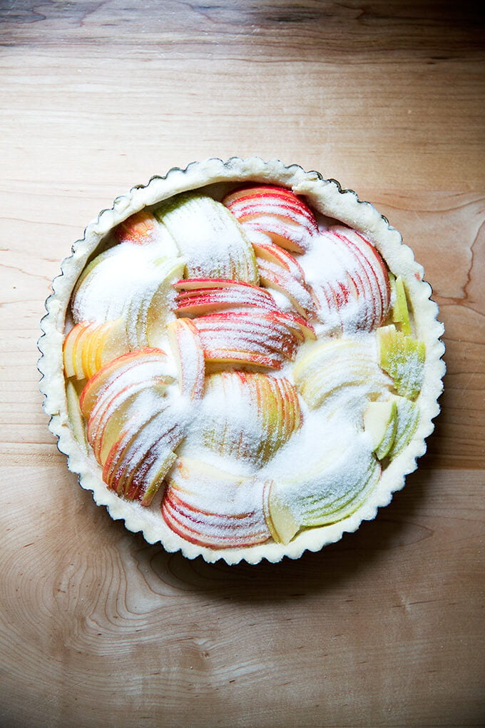 An unbaked French apple tart covered in sugar.