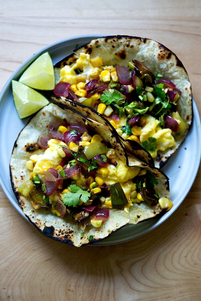 A plate of 2 egg tacos topped with roasted vegetable salsa.