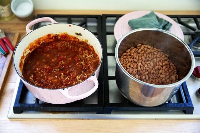 Two pots on the stove: one with vegetarian chili; the other with cooked Instant pot pinto beans.