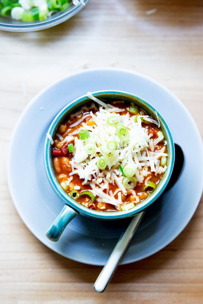 A bowl of stovetop vegetarian chili topped with cheese and scallions.