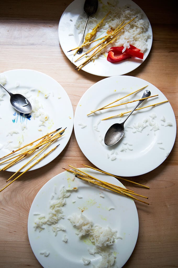 Four empty plates of easy Thai chicken satay with coconut rice.