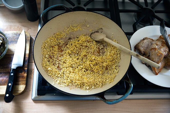 A skillet with orzo toasting in olive oil. 