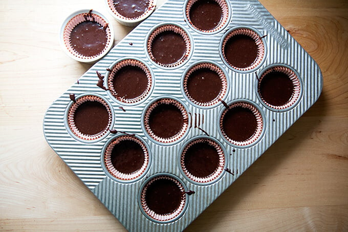 An overhead shot of a cupcake pan filled with chocolate cupcake batter. 