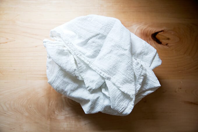 A bowl, lined with a tea towel, filled with a round of sourdough.