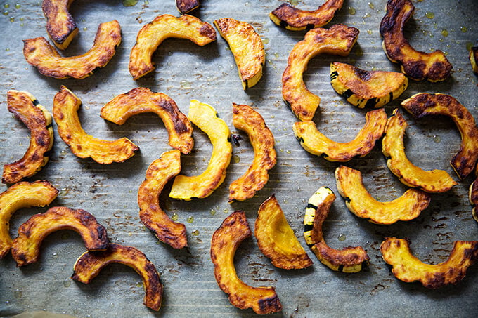 Roasted delicata squash slices on a sheet pan. 