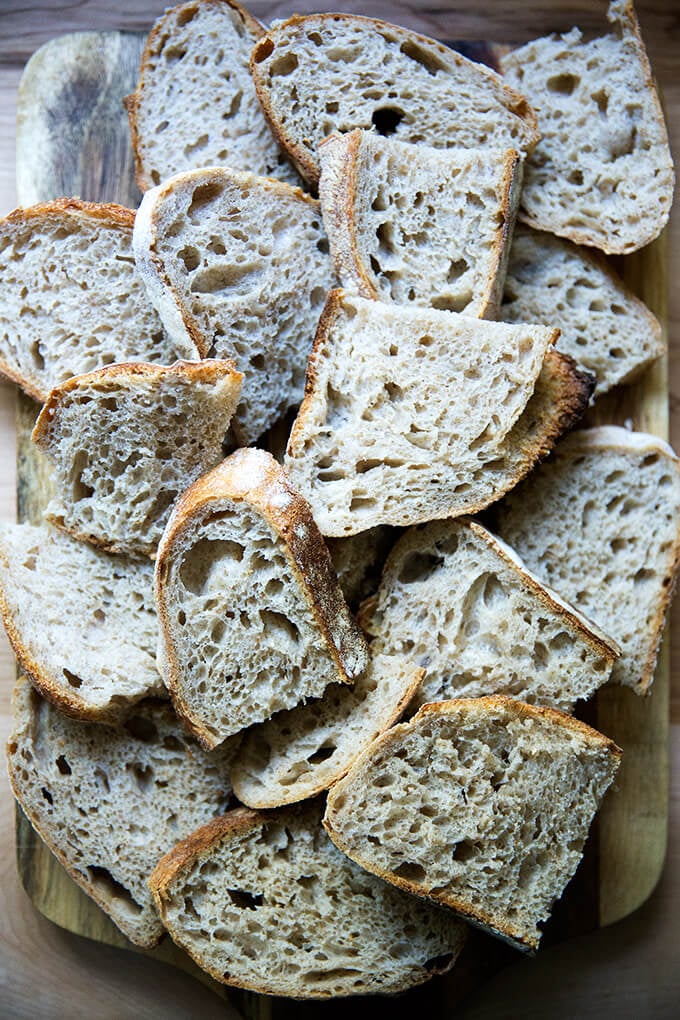 Ein Brett, beladen mit Scheiben von Sauerteigbrot mit hohem Feuchtigkeitsgehalt.