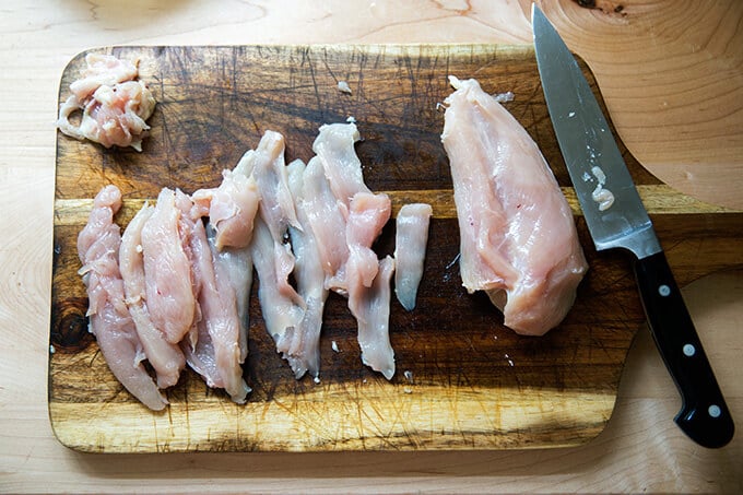 A board of thinly sliced chicken breast. 