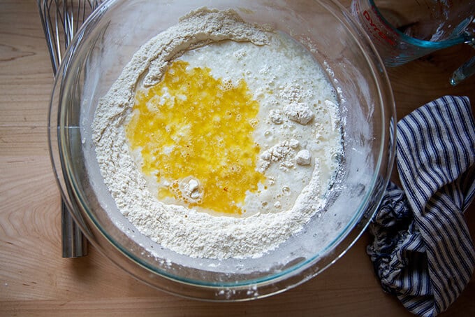 An overhead shot of a glass bowl with the wet ingredients added for the buttermilk pull-apart rolls.