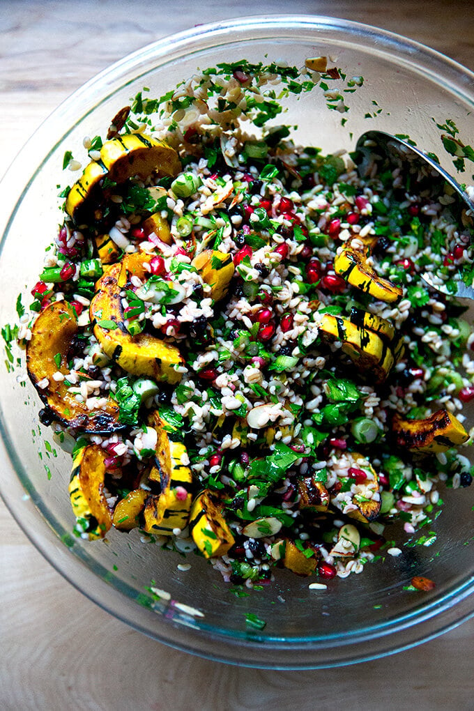 An overhead shot of a glass bowl filled winter tabbouleh and roasted delicata squash all tossed together.