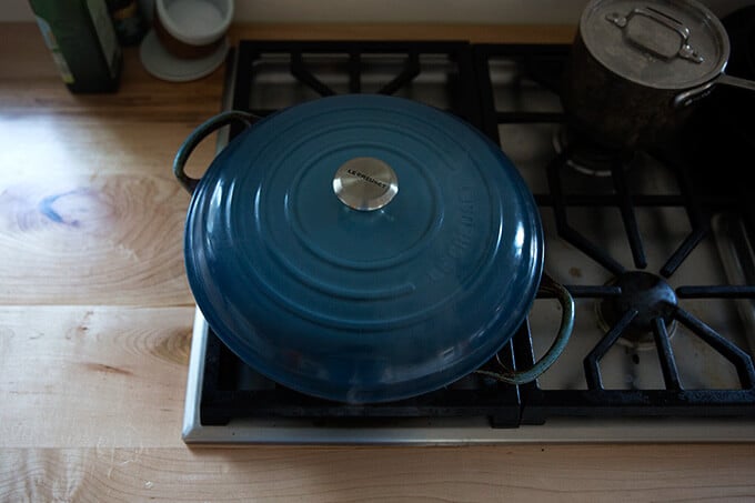 A covered Le Creuset braiser on the stovetop.