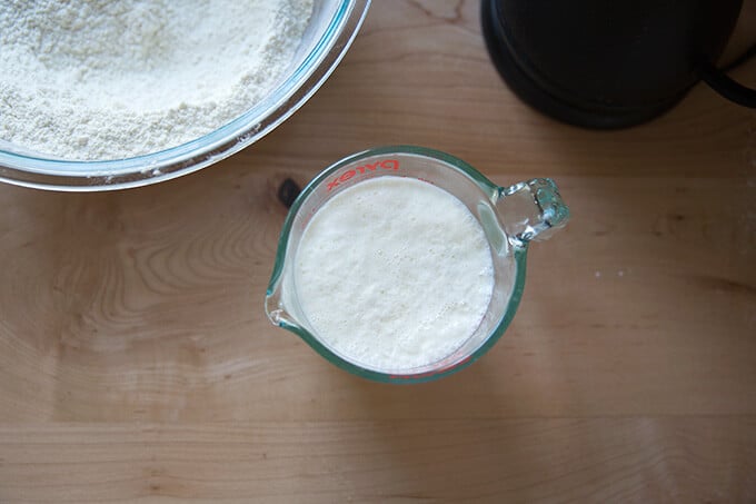 An overhead shot of a glass measure holding buttermilk and hot water.