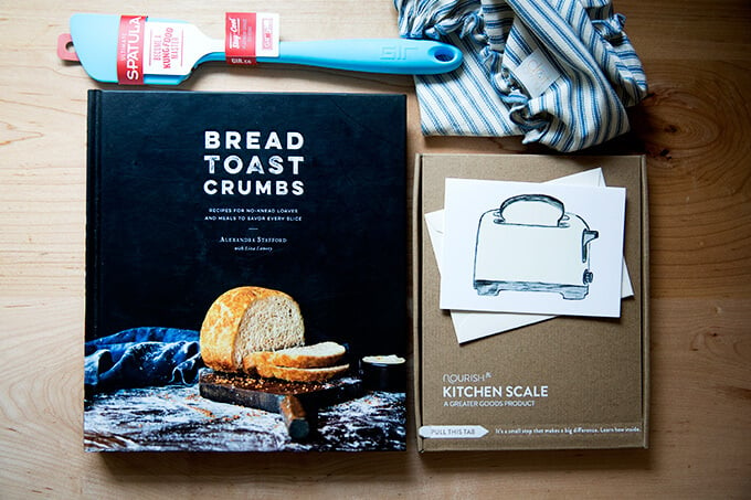 The contents of the Bread Toast Crumbs gift set: Bread Toast Crumbs, a spatula, a cloth bowl cover, a scale, and a card.