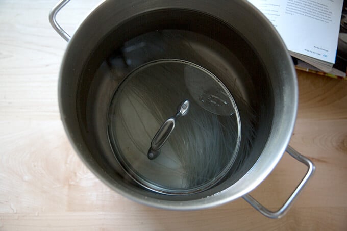 Japchae noodles soaking in a pot.
