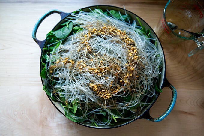 Soaked sweet potato noodles on top of spinach in a braiser.