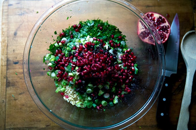 An overhead shot of a glass bowl filled with winter tabbouleh topped with pomegranate arils.