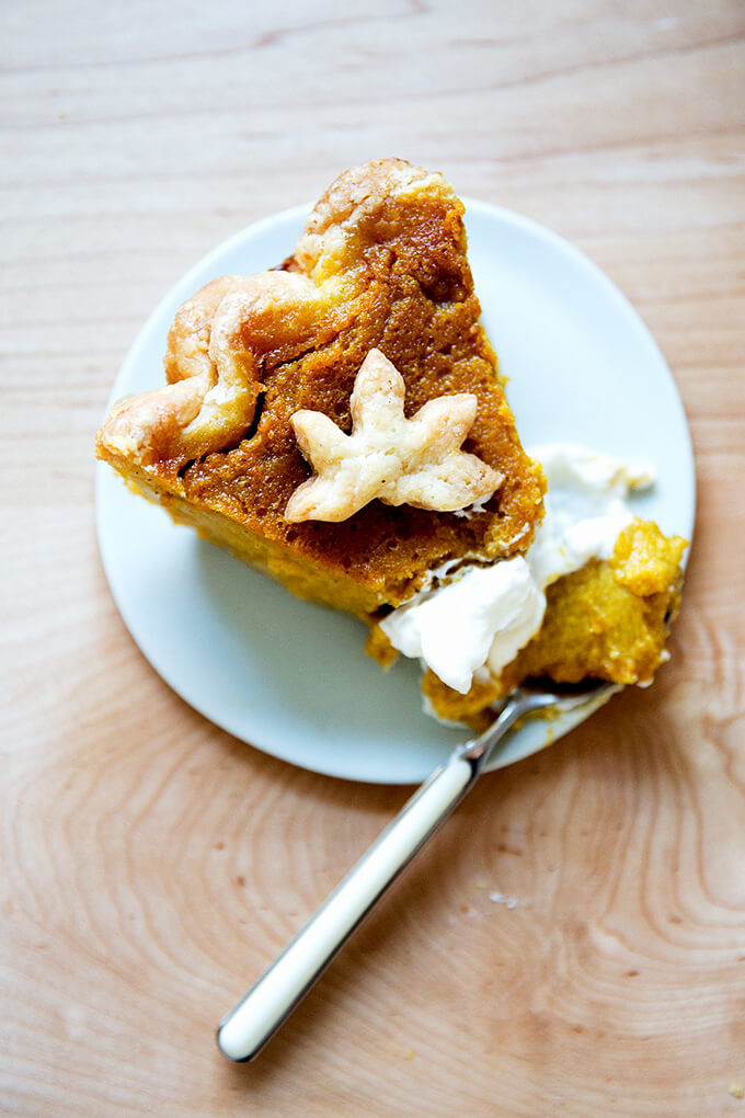 A slice of pumpkin pie on a plate with whipped cream.