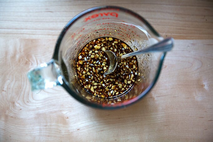 The sauce for the japchae in a liquid measure with a spoon.