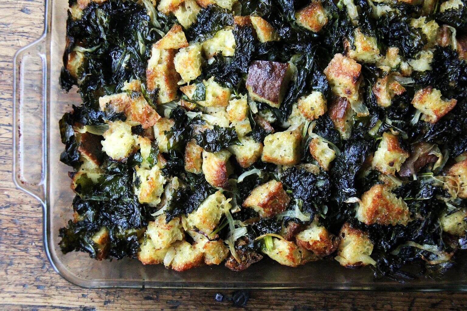 An overhead shot of just-baked kale and caramelized onions in a 9x13-inch pan.