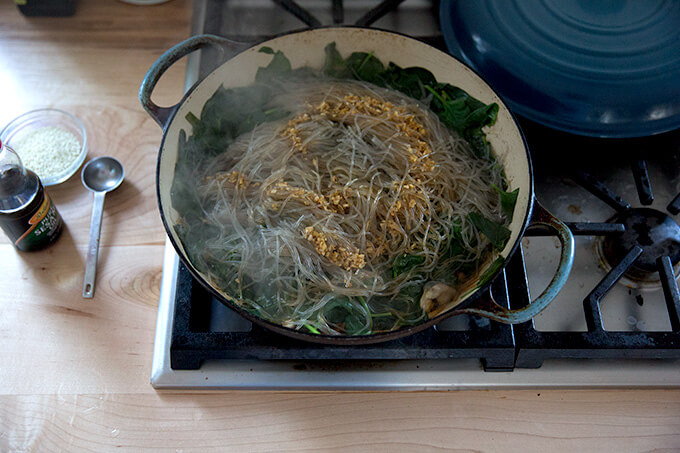 A braiser on the stovetop holding just-cooked japchae.