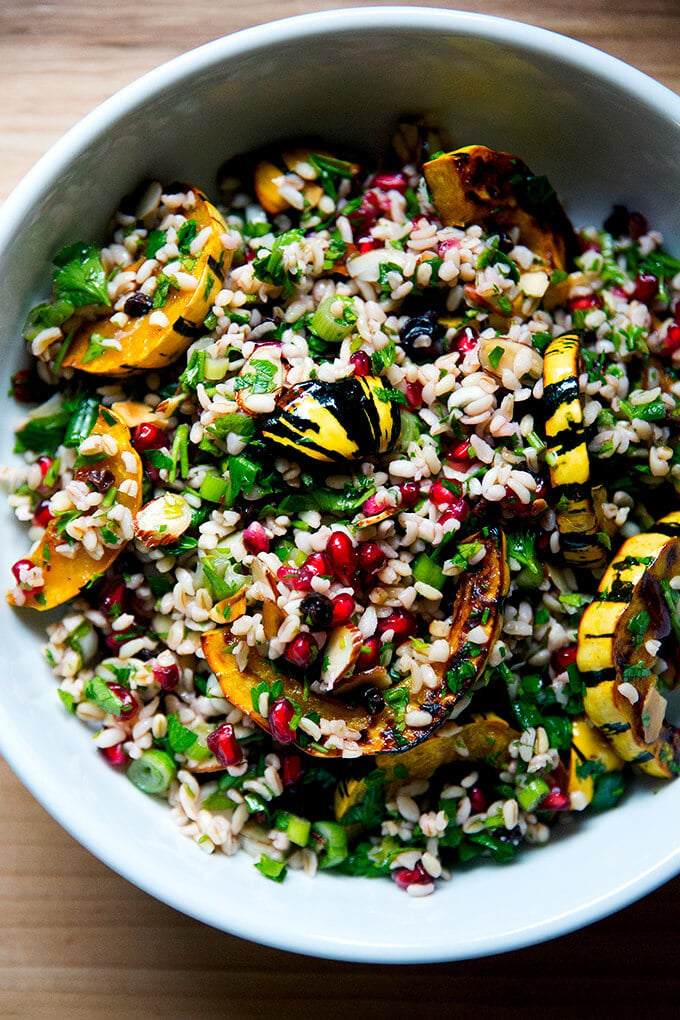A white serving bowl filled with winter tabbouleh and roasted delicata squash slices.