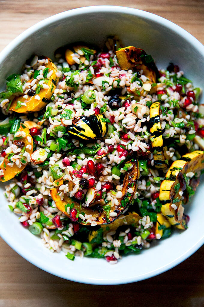 A white serving bowl filled with winter tabbouleh and roasted delicata squash slices.