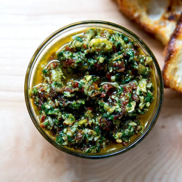 Sun-dried tomato and spinach pesto in a bowl aside bread.