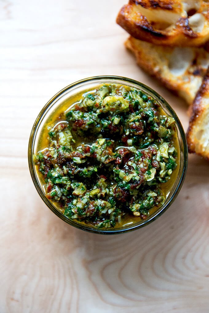 Sun-dried tomato and spinach pesto in a bowl aside bread.