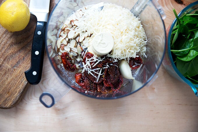 A food processor with the ingredients to make sun-dried tomato pesto.