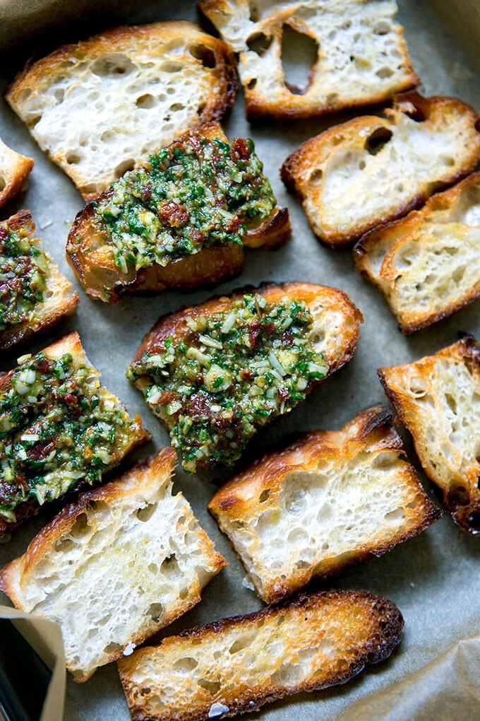 Toast points topped with sun-dried tomato pesto on a sheet pan.