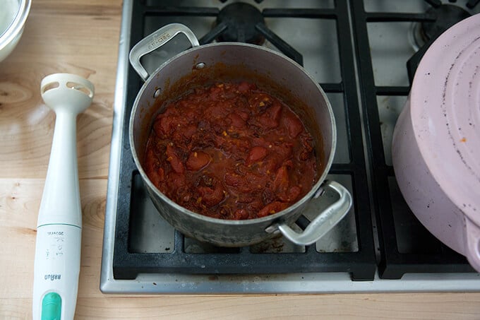 A saucepan filled with simmered vodka sauce aside an immersion blender.